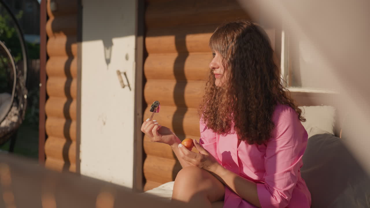 Woman On Porch With Food And Smile, Casual Outdoor Meal With Woman During Golden Hour Light, Woman Calmly Eating From Jar On Porch During Warm Evening Sunlight With Cheerful Expression
