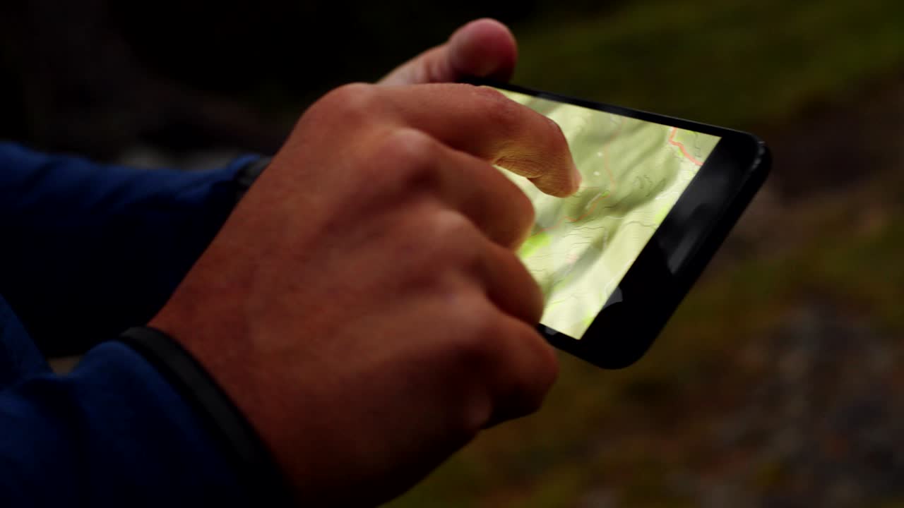 Uomo che si orienta usando la tecnologia GPS e le mappe sullo smartphone. Gruppo di amici in un'avventura estiva nella natura montana all'aperto. Viaggio esplorando Alpi, Dolomiti, Italia. Video 4k slow motion a 60p.