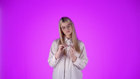 mujer rubia descarada hace manicura, limpieza de uñas, fondo violeta aislado