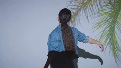 woman visiting immersive art exhibition interacting with images of palm leaves being projected onto wall