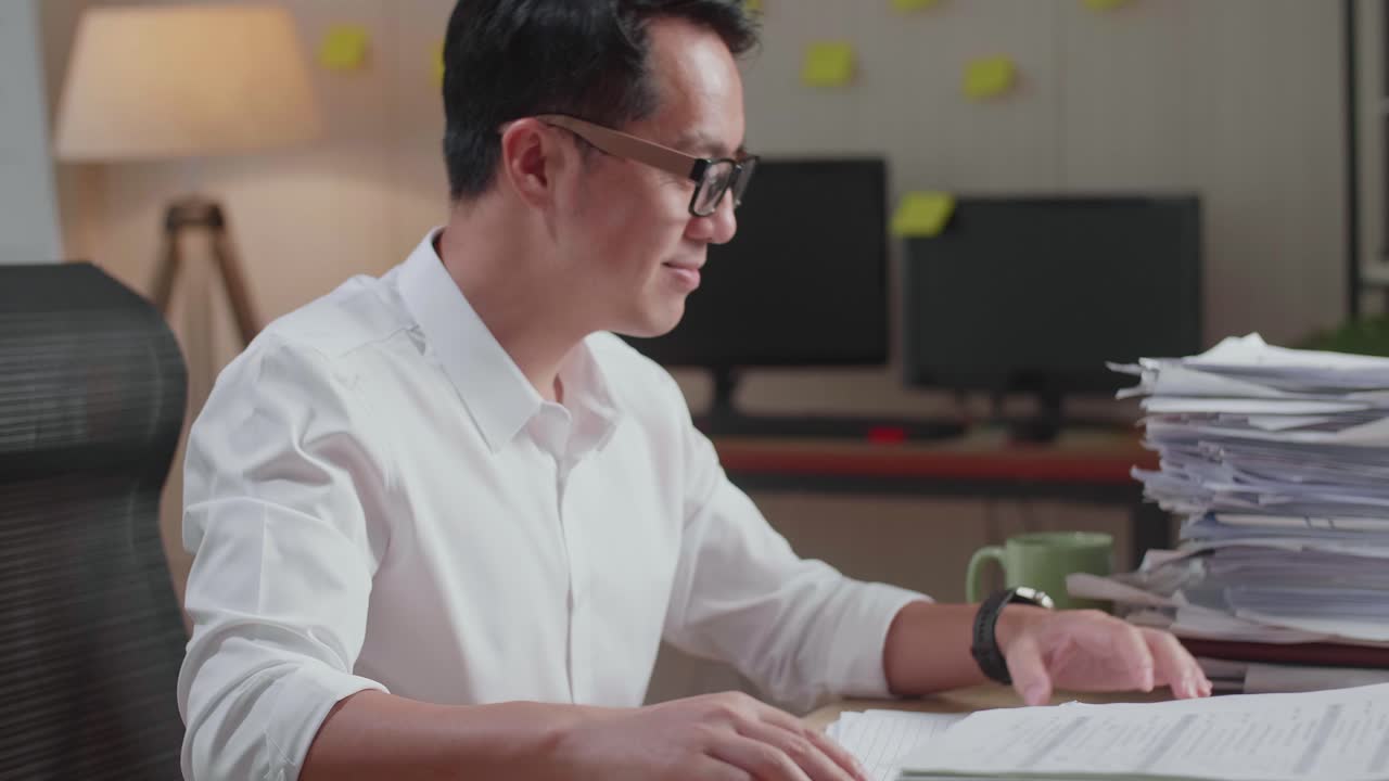 행복한 아시아 남자가 사무실에서 문서 작업을 마치고 축하하는 클로즈업