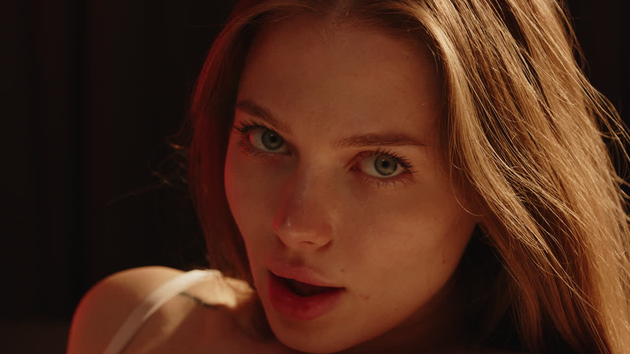 Stunning portrait of a sensual woman with beautiful blue eyes enticingly looking at the camera in slow motion