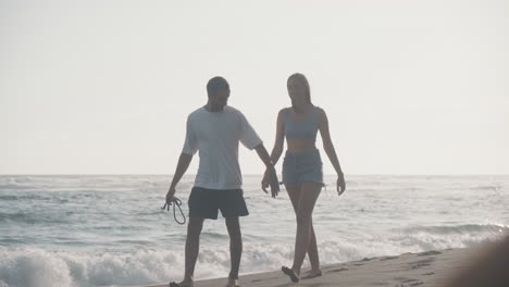 couple walking hand in hand on the beach at sunset