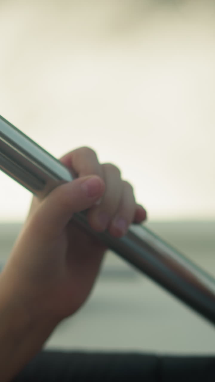 작은 아이의 손은 금속 바를 들고 모터 보트를 타고 여행합니다. 여름 휴가 동안 안전 장비와 함께 요트를 타고 있습니다. 관광 활동.