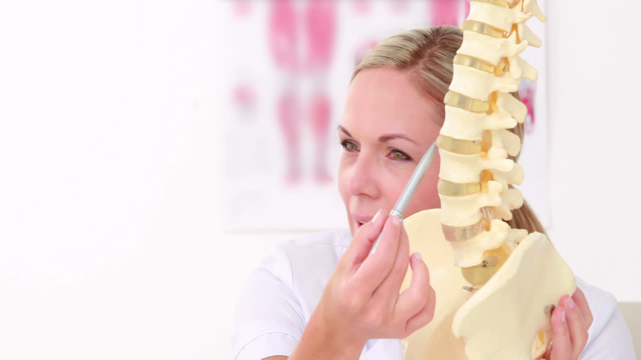 médico mostrando la columna anatómica a su paciente