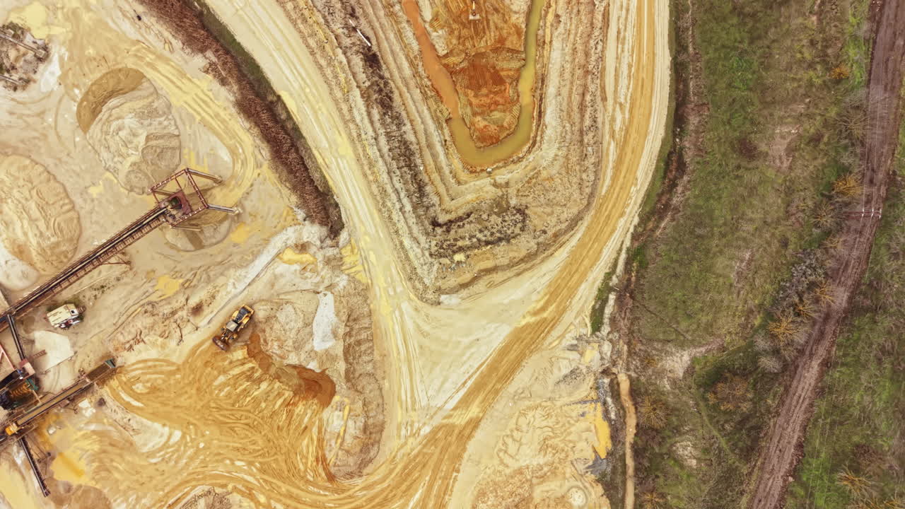 Ausgrabungsstätte mit Maschinen, die Erde bewegen und Wege in einer Lehm- und Sandlandschaft mit Bäumen in der Nähe anlegen
