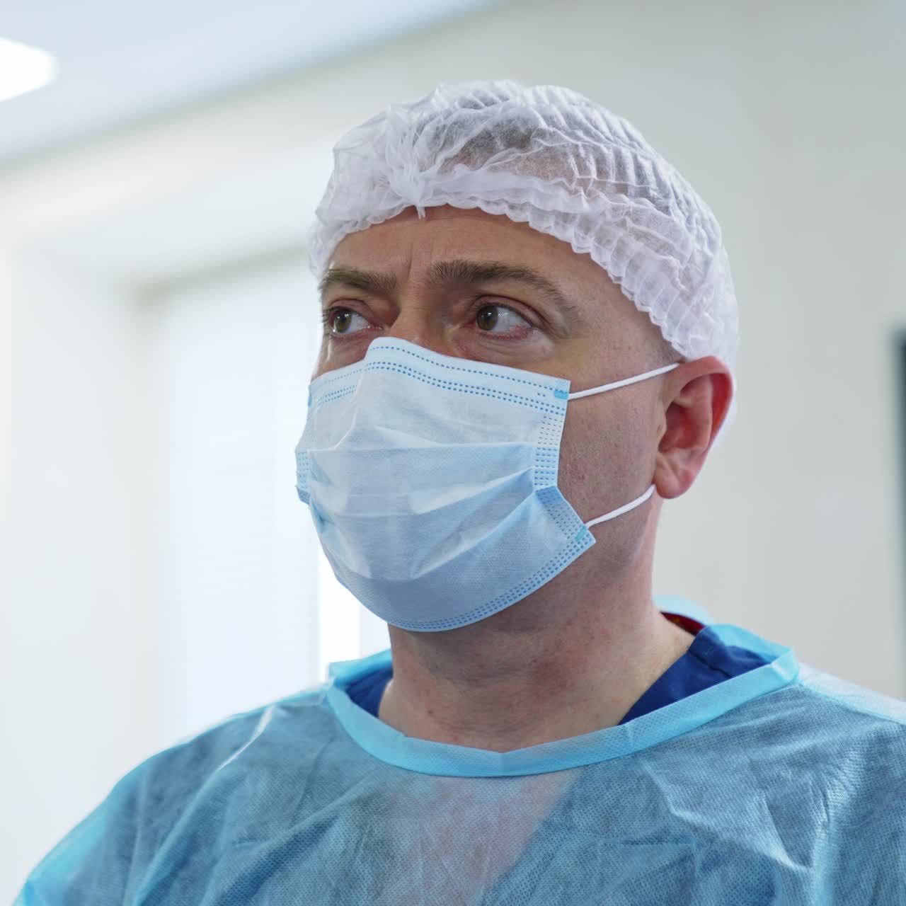 Surgeon in mask comments on something. Experienced medical doctor looking aside and talking. Portrait close up