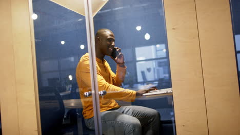 african american businessman using smartphone and computer in office, slow motion, copy space