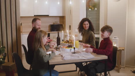 pareja y sus hijos rezan y bendicen la mesa antes de la cena familiar de navidad