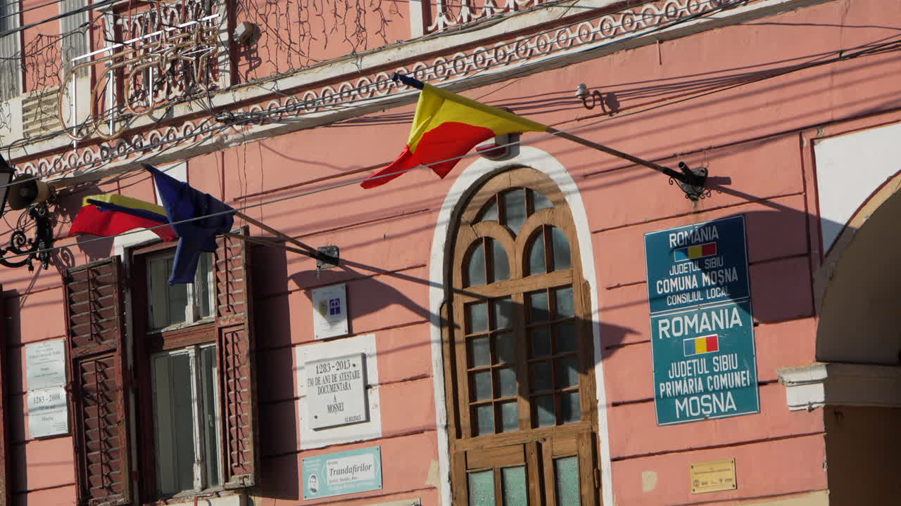 European and Romanian flag waving in the facade of a building. Slow motion