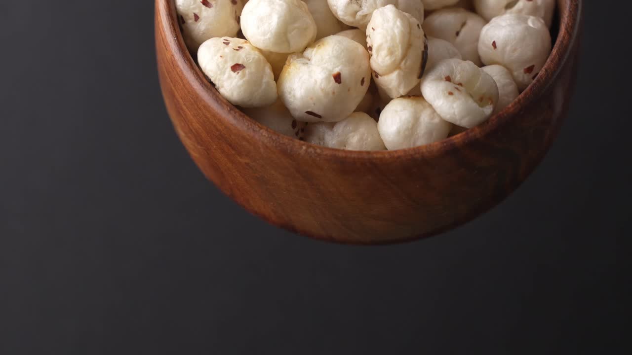 Primo piano di makhana che cade da una ciotola di legno