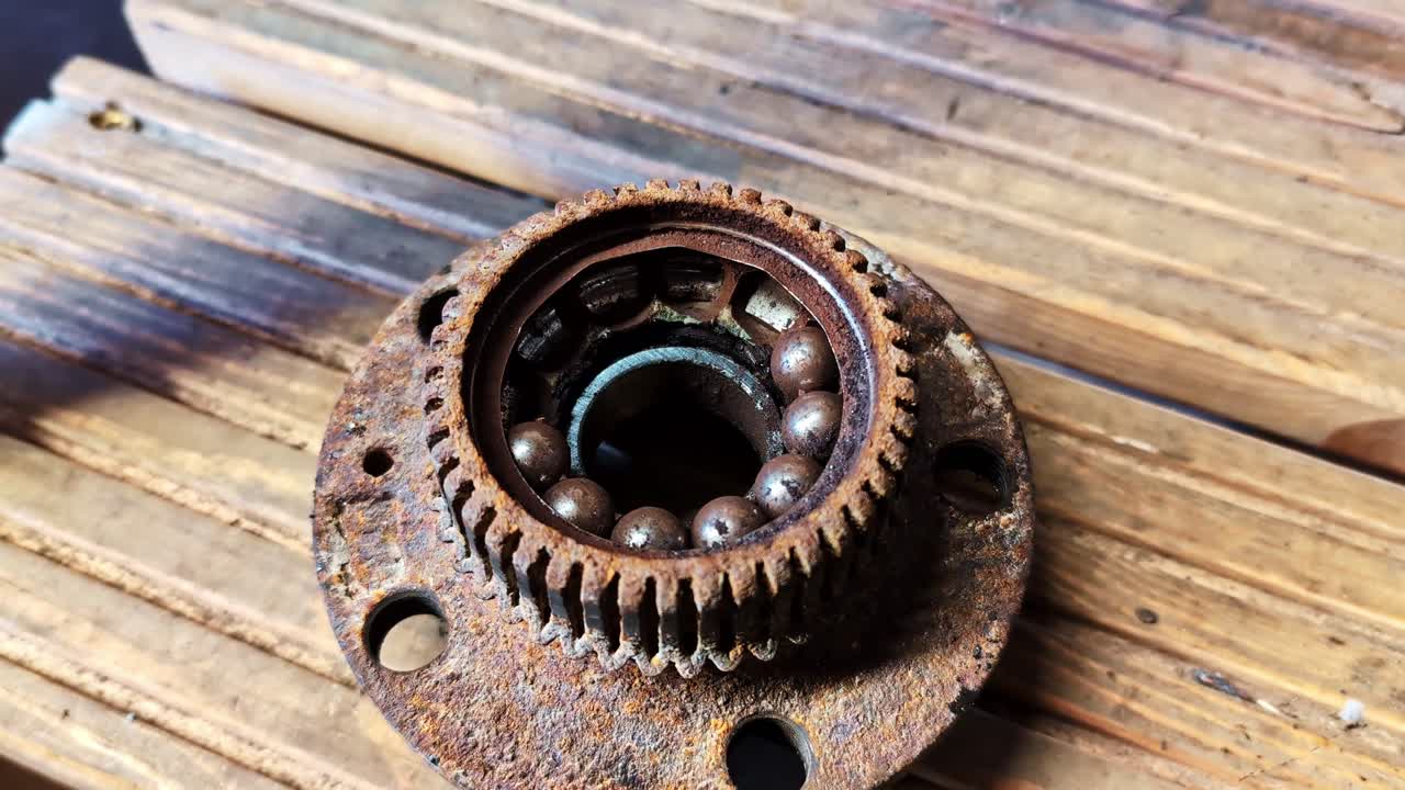 Mozzo del cuscinetto della ruota arrugginito e cuscinetto a sfera che mostrano corrosione e danni significativi.