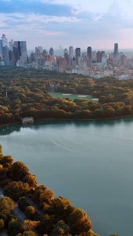 view of marvelous new york skyscrapers from the side of central park. drone footage above the jaqueline kennedy onassis reservoir at sunset.
