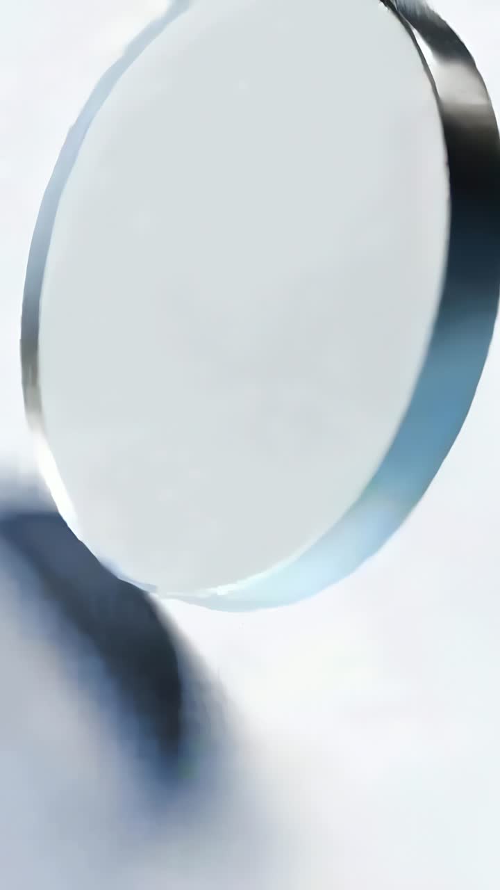 Vertical video: Tilting frosted disc rotating with camera shift on white surface revealing blue rim