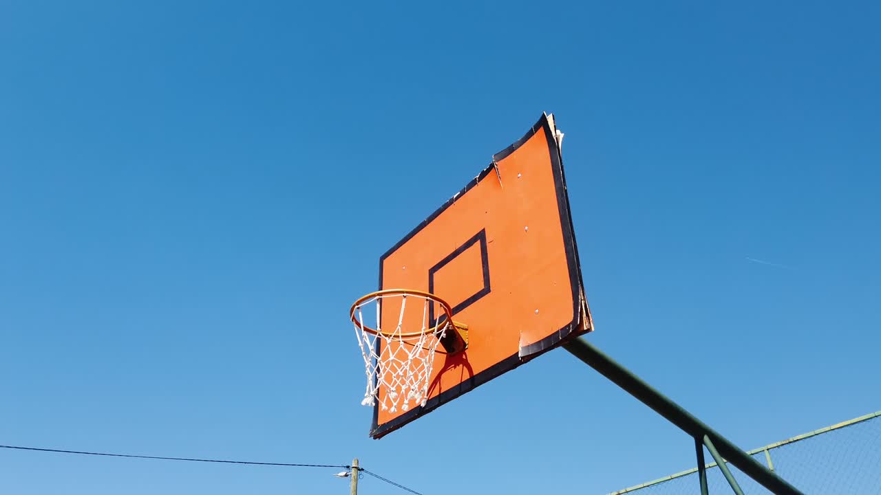 anillo de baloncesto viejo y tablero en el patio de recreo en un día soleado