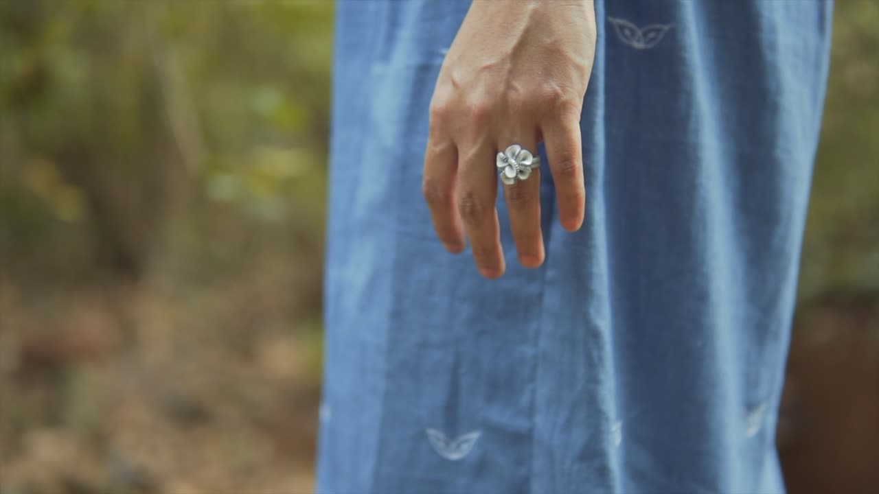 In this close-up detail shot, an unrecognizable woman's hand wearing a beautiful floral ring