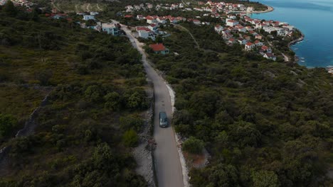 van driving at croatian coast near kanica. smooth aerial shot with sea and village behind