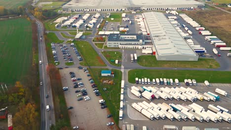 Warehouses,-huge-logistics-center-near-the-highway,-view-of-a-large-number-of-cargo-trailers-and-containers,-international-cargo-transportation,-aerial-view