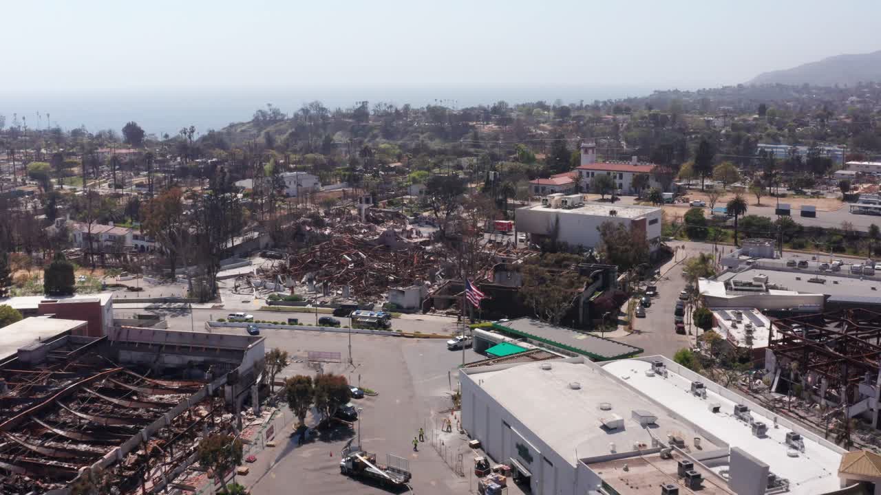 Low push-in aerial shot of the United States flag in downtown Pacific Palisades after the Palisades Fire in Los Angeles, California. 4K
