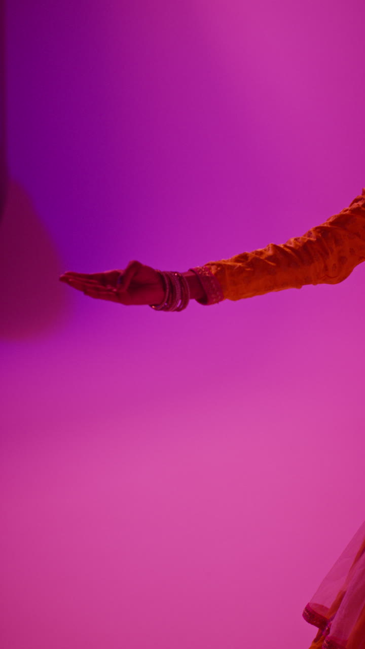 video de estudio vertical de una bailarina de kathak que realiza un baile vestida con el vestido tradicional indio contra un fondo púrpura 2