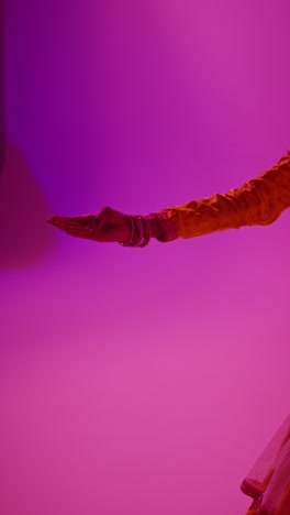 vertical video studio shot of female kathak dancer performing dance wearing traditional indian dress against purple background 2