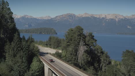 jeep driving over lakeside bridge in beautiful mountainous nature, wide angle