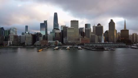 4k 30fps rastreando imágenes aéreas de drones del horizonte de la ciudad de san francisco y la bahía de sf california - rascacielos épicos, muelles y puertos, edificio del puerto de san francisco, puesta de sol tormentosa, costa frente al mar