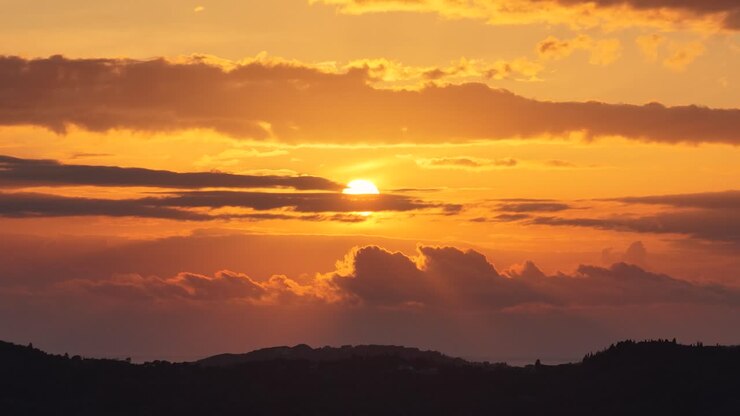 Raggi di sole che trafiggono nuvole scure e pesanti al tramonto, silhouette drammatica di colline, maestoso cielo serale aereo in Grecia, sfondo di paesaggio naturale suggestivo, luce spirituale