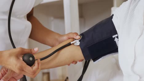 female doctor measuring blood pressure of mature woman in bedroom 4k