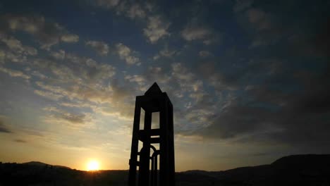 a-time-lapse-of-clouds-moving-above-a-tower-at-sunset