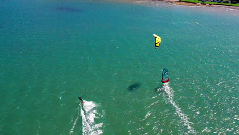 kiteboarder and windsurfer surf near joaquina beach, brasil, aerial shot