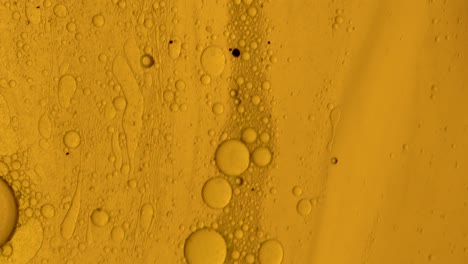 gel aceitoso dorado que fluye sobre una superficie similar a una mancha con burbujas de aceite