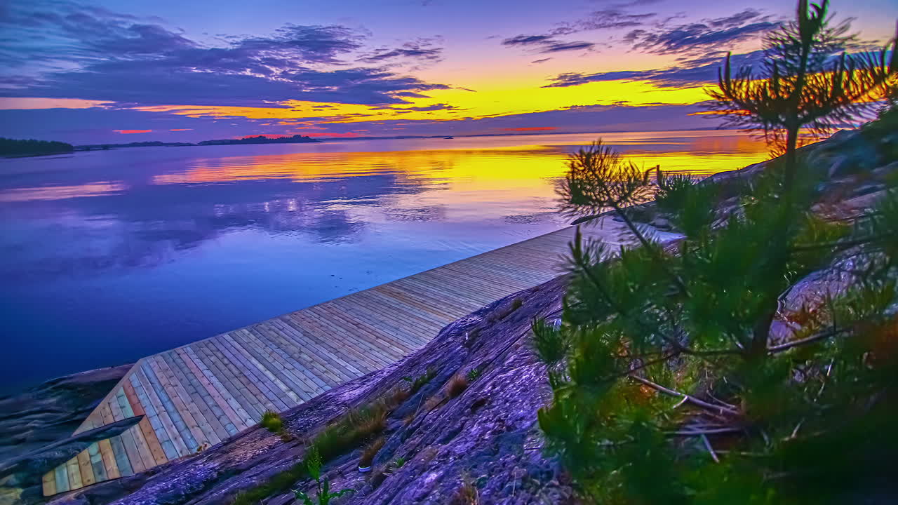 vista de la puesta de sol amarilla sobre el cielo azul al lado del lago azul al lado del embarcadero de madera en las rocas en el lapso de tiempo en la noche