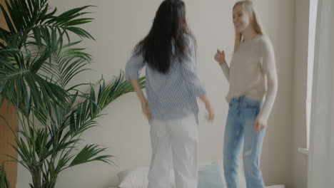 two women jumping on a bed