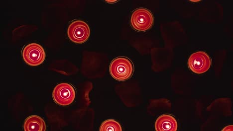 Overhead-Shot-Of-Romantic-Lit-Red-Candles-Revolving-On-Background-Covered-In-Rose-Petals-1