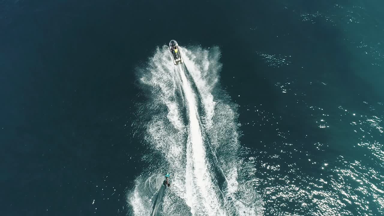 Jet Ski and surf rider on jet skiing on tropical blue and green sea waterscape. Top down aerial footage of sport activity with ocean waves ripple. beautiful high adrenaline and extreme sports scene.