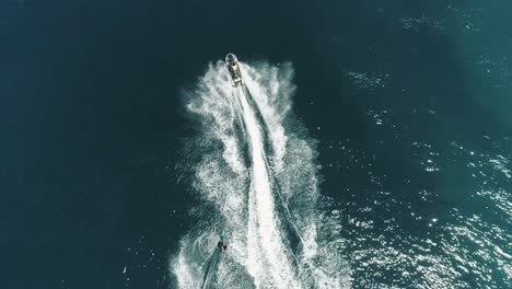 jet ski and surf rider on jet skiing on tropical blue and green sea waterscape. top down aerial footage of sport activity with ocean waves ripple. beautiful high adrenaline and extreme sports scene.