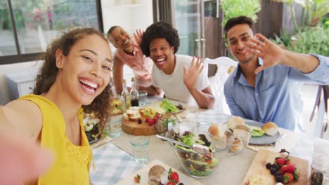 grupo de diversos amigos masculinos y femeninos haciendo una llamada de video en la fiesta de la cena en el patio