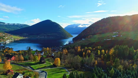 aerial view of beautiful traditional wooden church in norway surrounded by autumnal trees beside fjord lake