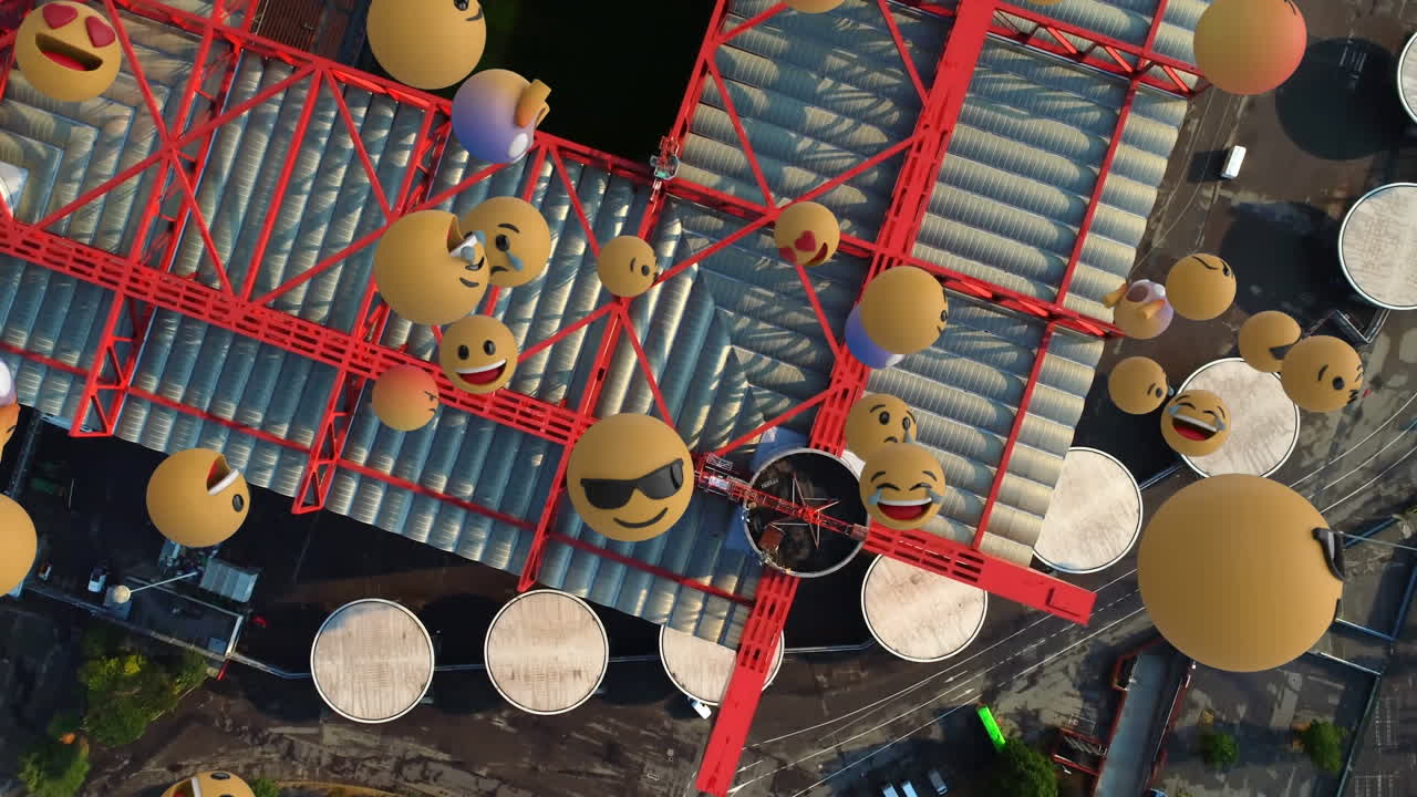 여러 얼굴 이모지 의 디지털 구성 이 도시 의 창고 의 공중 전망 에 대항 하여 떠다니고 있다