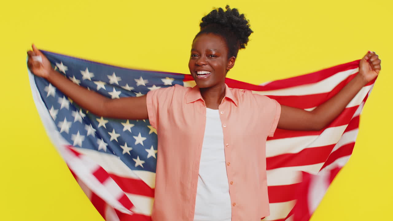 Jeune femme noire saluant et s'enveloppant dans le drapeau américain, célébrant les droits de l'homme et les libertés