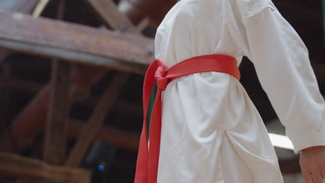 girl tying orange belt on kimono and folding arms behind back