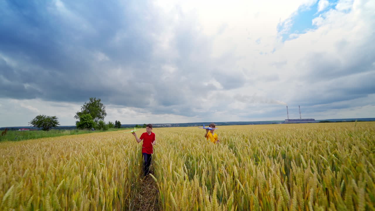 Boys with toys on a field. Brothers running with toy planes among the yellow wheat field. Cheerful children playing among nature.