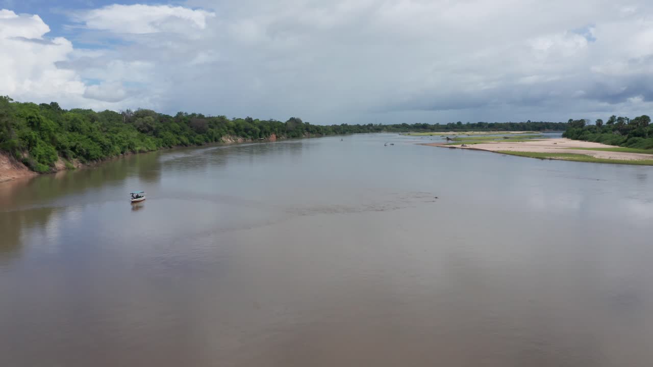 Aerial drone shot orbiting around a boat and some hippopotamus in a river in Selous, Tanzania
