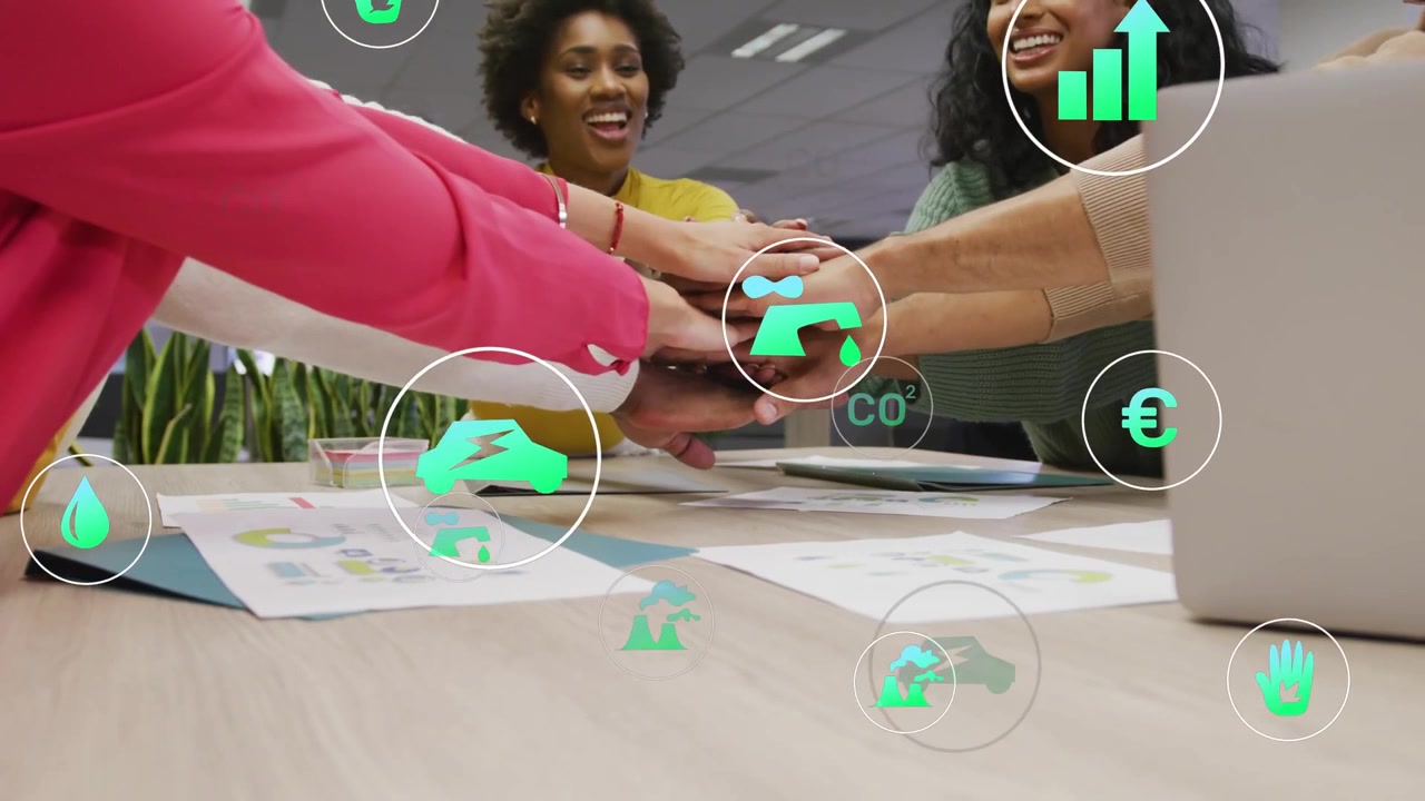 On cue, team stacking palms around meeting table, green icons over charts supporting ESG goals