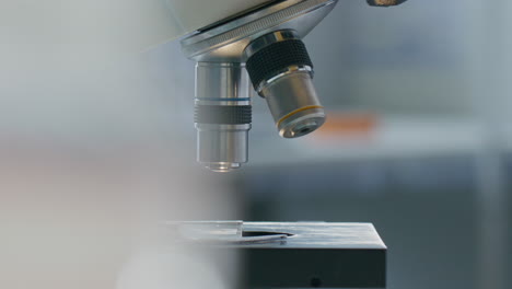 Close-Up of Microscope Objective Lens Being Lowered to Specimen Slide