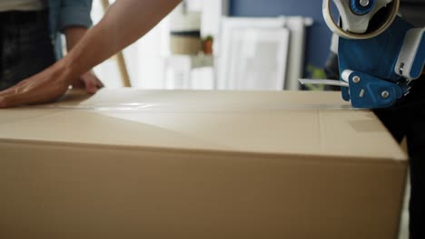 tracking video of couple packing cardboard boxes while moving house.