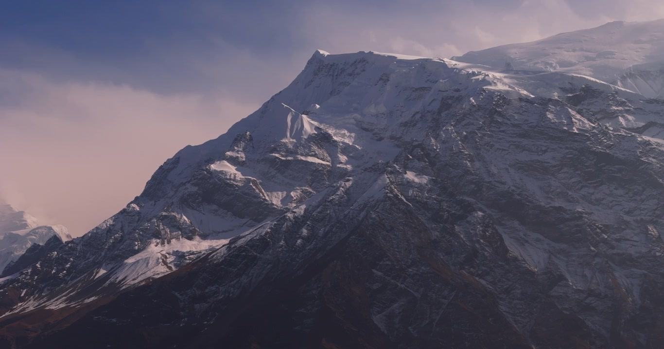 Circuito dell'Annapurna, Manang, Nepal, scatto panoramico con drone attraverso le maestose cime montuose innevate della catena dell'Annapurna sotto un cielo azzurro e limpido.