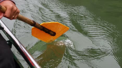 hand rowing a boat on calm water