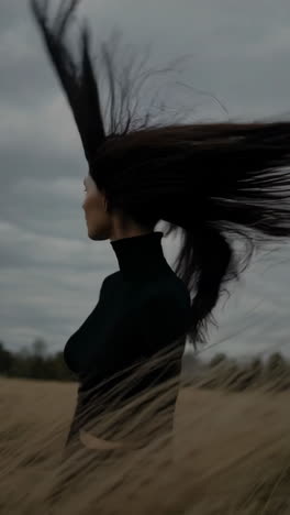 dramatic portrait of a woman with long hair blowing in the wind in a field